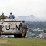 UN peacekeepers near a UN armored vehicle overlooking a rural settlement in DRC for MONUSCO peacekeeping operations.